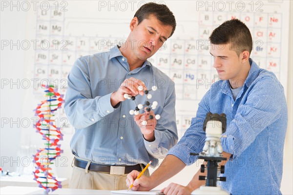 Teacher and teenage (16-17) student in chemistry lab.