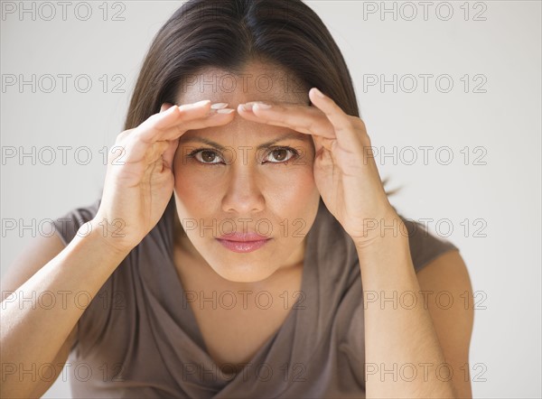 Studio shot of woman shielding eyes.