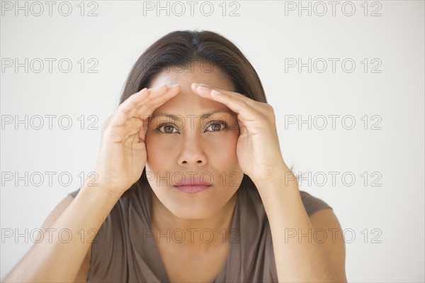 Studio shot of woman shielding eyes.