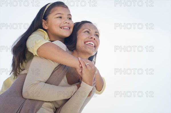 Mother giving piggyback ride to her daughter (10-11).