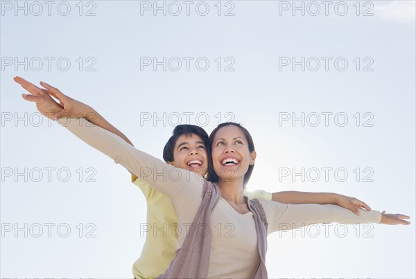 Mother giving piggyback ride to her son (12-13).