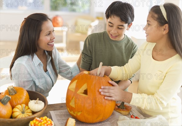 Mother with son (12-13) and daughter (10-11) doing Jack o lantern.