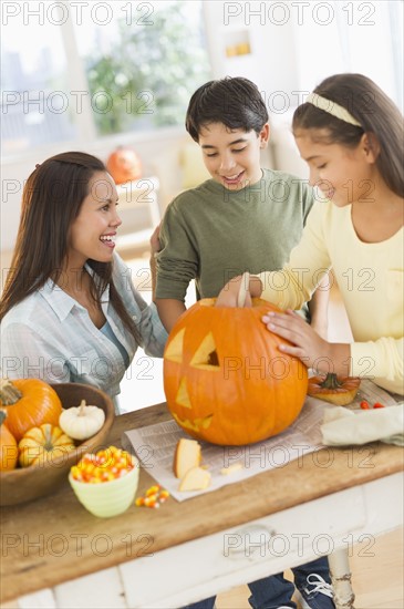 Mother with son (12-13) and daughter (10-11) doing Jack o lantern.