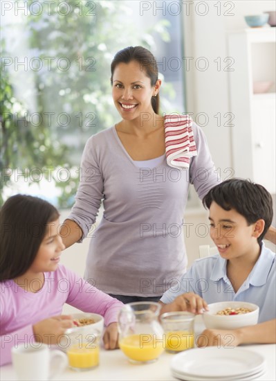 Mother with son (12-13) and daughter (10-11) having breakfast.