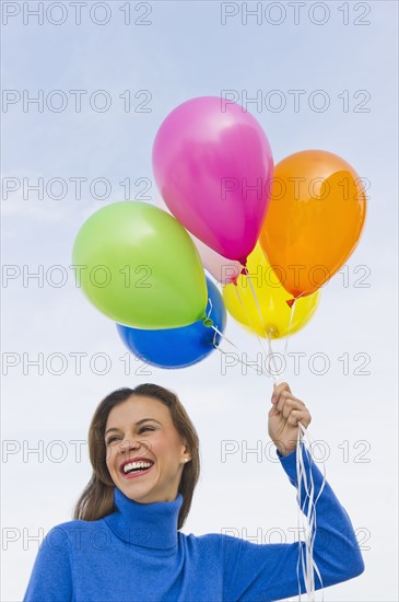 Smiling woman holding balloons.