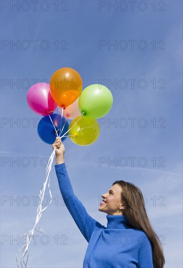Smiling woman holding balloons.