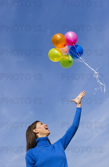 Smiling woman loosing balloons.