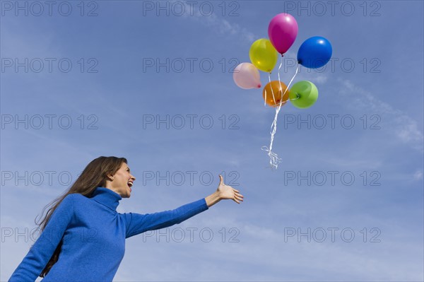 Smiling woman loosing balloons.