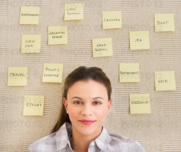 Woman lying on carpet with adhesive notes around head.