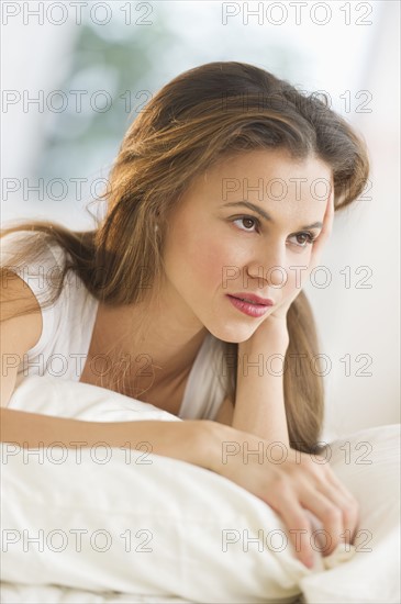 Sad woman lying on bed.