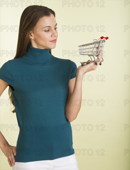 Studio shot of woman holding small shopping cart.