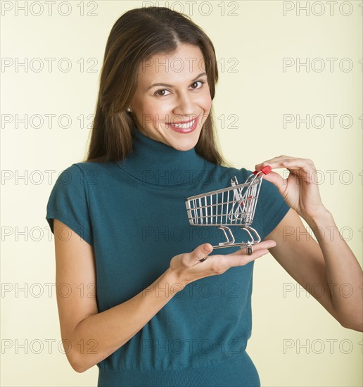 Studio shot of woman holding small shopping cart.