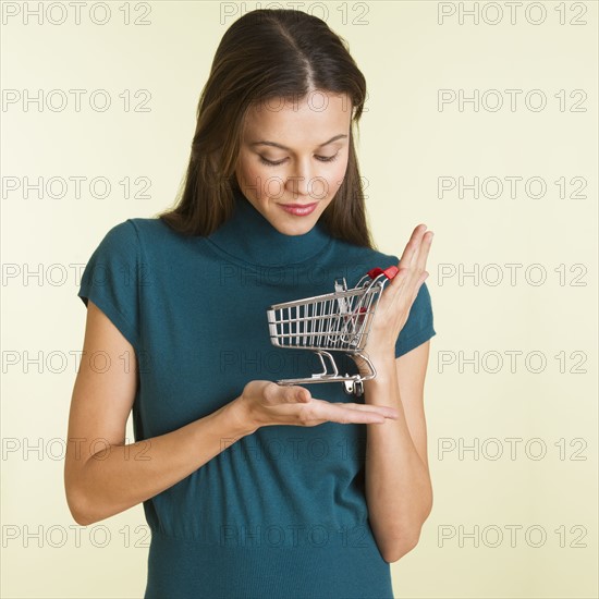 Studio shot of woman holding small shopping cart.