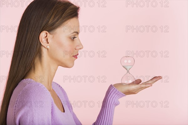 Studio shot of woman holding small hourglass.