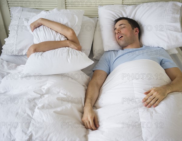 Couple in bed, man snoring.