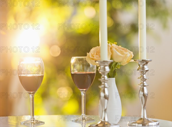 Still life with wine in glasses, candles and bouquet on table.