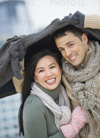 Couple walking with jacket over heads.