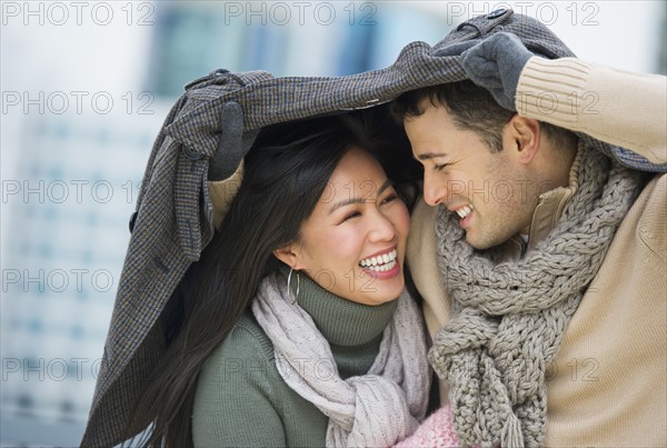 Couple walking with jacket over heads.