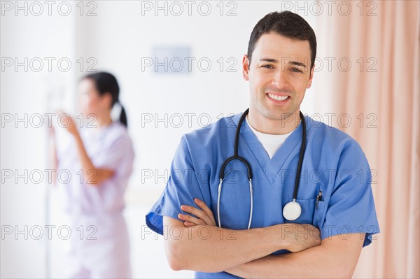 Portrait of doctor, nurse in background.
