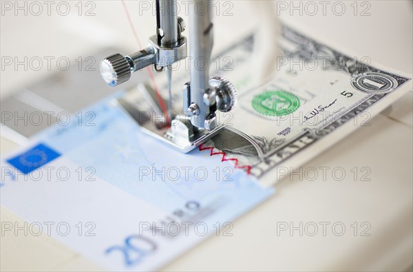 Halves of banknotes being sewed with sewing machine.