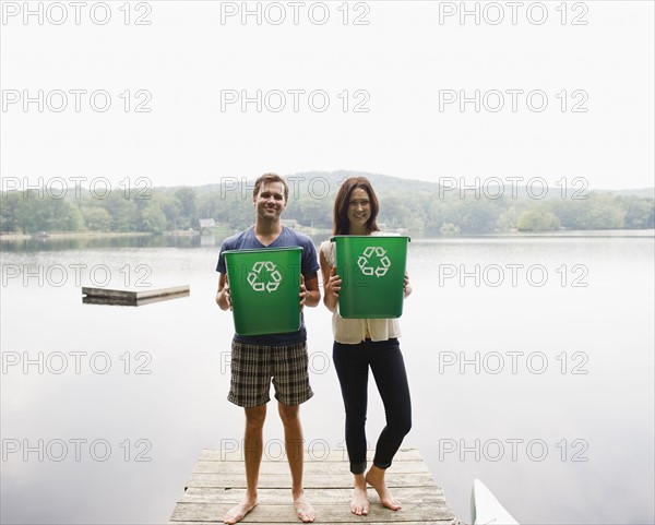USA, New York, Putnam Valley, Roaring Brook Lake, Couple standing on pier with recycling bins. Photo : Jamie Grill