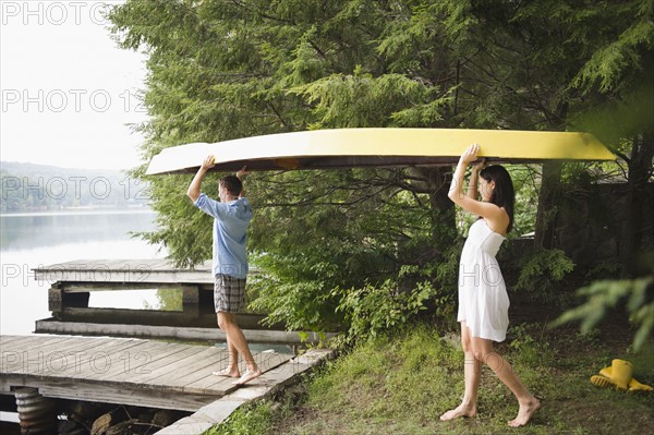 Roaring Brook Lake, Couple carrying boat by lake. Photo : Jamie Grill
