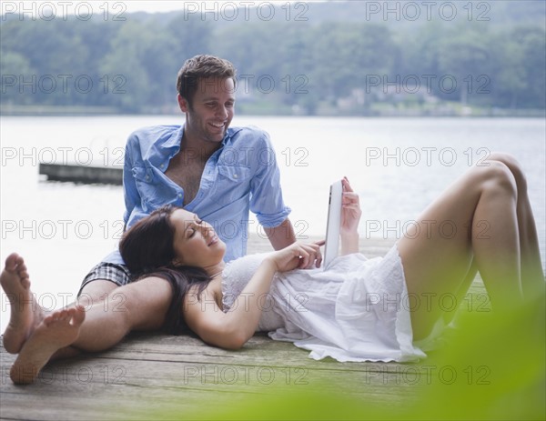 USA, New York, Putnam Valley, Roaring Brook Lake, Couple relaxing on pier by lake. Photo: Jamie Grill