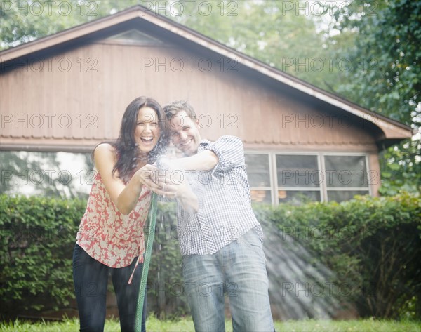 USA, New York, Putnam Valley, Roaring Brook Lake, Couple playing with hose. Photo: Jamie Grill