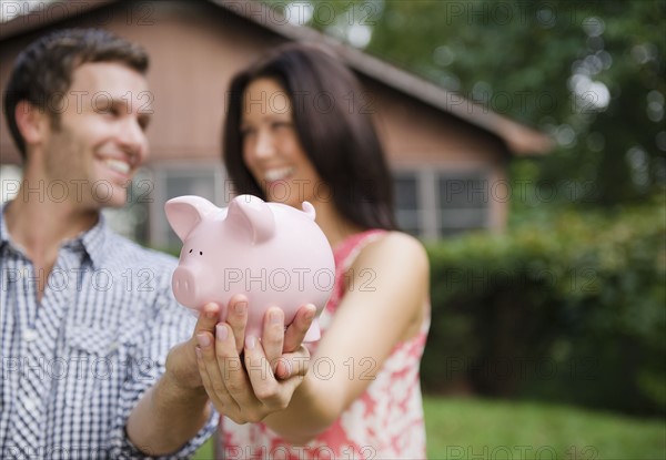 USA, New York, Putnam Valley, Roaring Brook Lake, Couple holding piggy bank. Photo : Jamie Grill