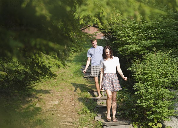 USA, New York, Putnam Valley, Roaring Brook Lake, Couple walking down steps among trees. Photo: Jamie Grill