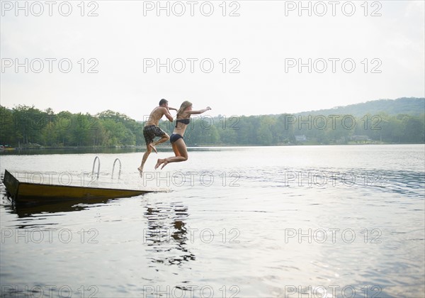 USA, New York, Putnam Valley, Roaring Brook Lake, Couple jumping from pier to lake. Photo : Jamie Grill