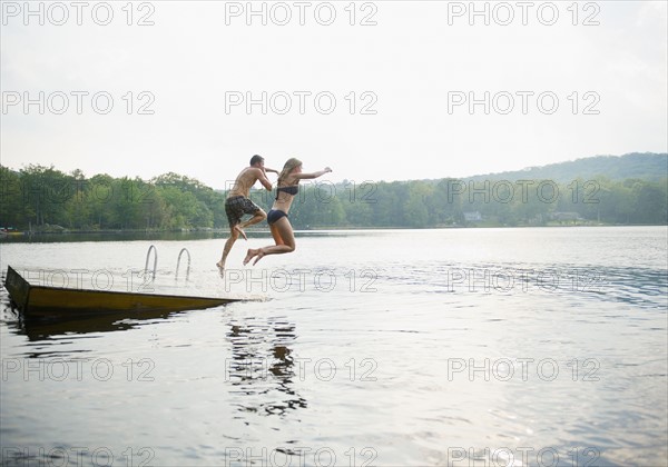 USA, New York, Putnam Valley, Roaring Brook Lake, Couple jumping from pier to lake. Photo: Jamie Grill