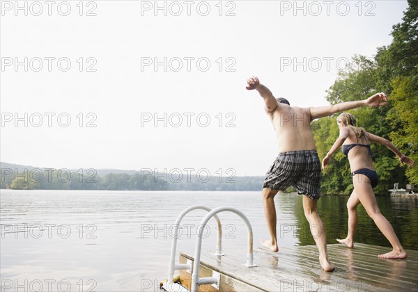 USA, New York, Putnam Valley, Roaring Brook Lake, Couple about to jump from pier to lake. Photo : Jamie Grill
