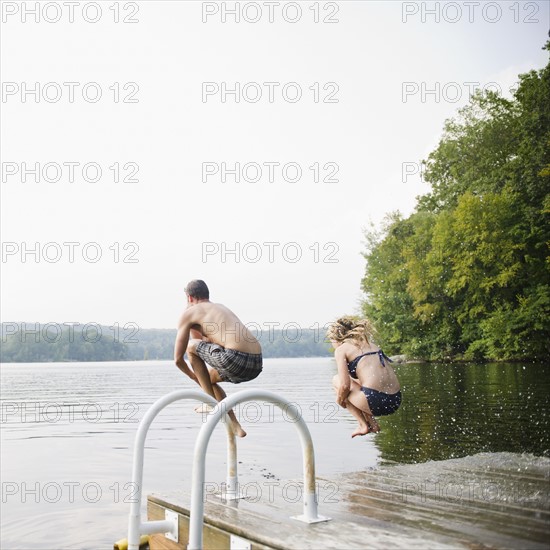 USA, New York, Putnam Valley, Roaring Brook Lake, Couple jumping from pier to lake. Photo : Jamie Grill