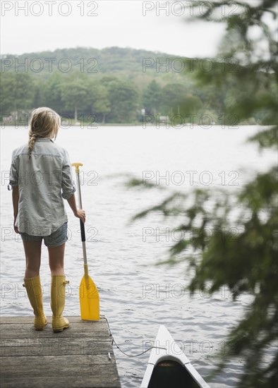 USA, New York, Putnam Valley, Roaring Brook Lake, Woman standing on pier with paddle. Photo: Jamie Grill
