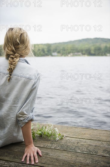USA, New York, Putnam Valley, Roaring Brook Lake, Rear view of woman sitting on pier by lake. Photo : Jamie Grill