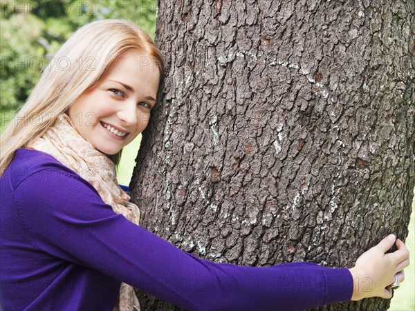 USA, New York, New York City, Manhattan, Central Park, Young woman embracing tree. Photo: Daniel Grill