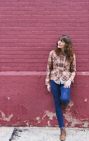 Woman leaning against purple brick wall. Photo: Daniel Grill