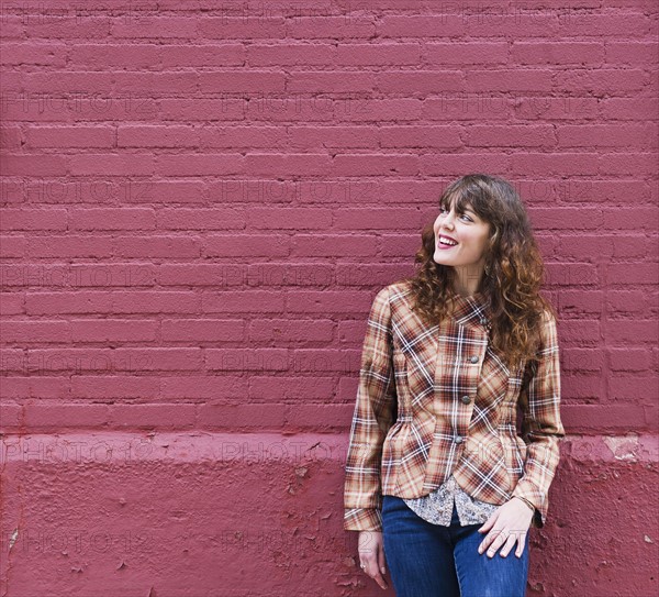 Woman leaning against purple brick wall. Photo : Daniel Grill