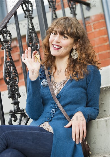 Portrait of woman sitting on stairs and holding keys. Photo : Daniel Grill