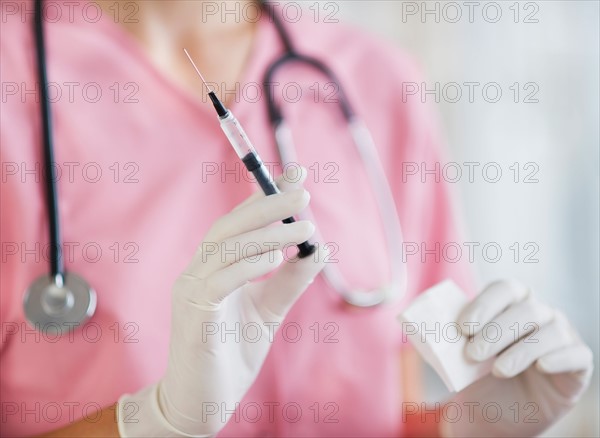 Close up of hands of female nurse holding syringe and gaze. Photo : Daniel Grill