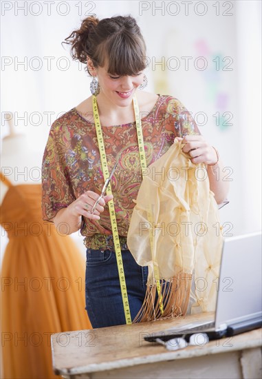 Female fashion designer working in studio. Photo : Daniel Grill