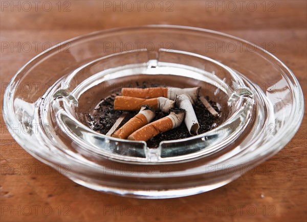 Close up of cigarette butts in glass ashtray. Photo : Daniel Grill