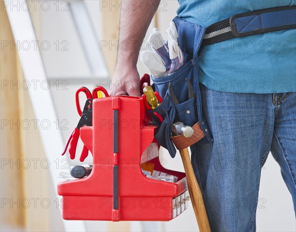 Close up of construction worker carrying tool box. Photo : Daniel Grill