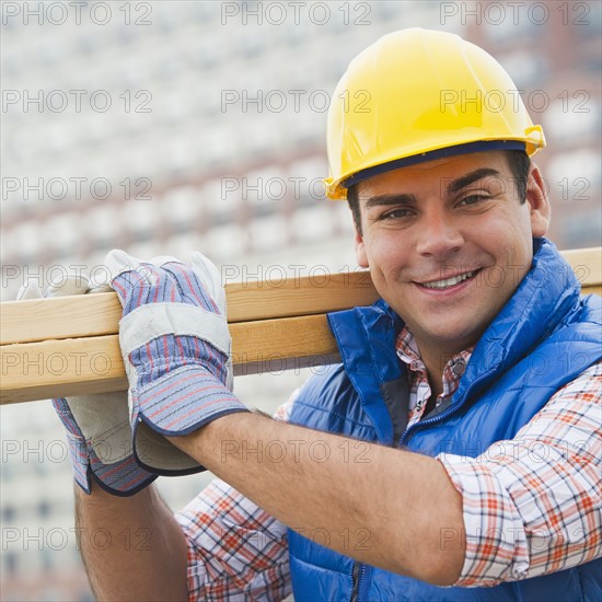 Construction worker carrying planks on construction site. Photo: Daniel Grill