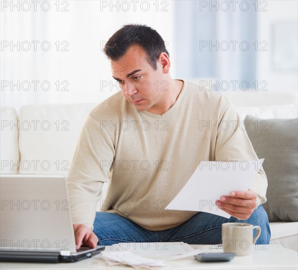 Portrait of man doing paperwork in living room. Photo : Daniel Grill