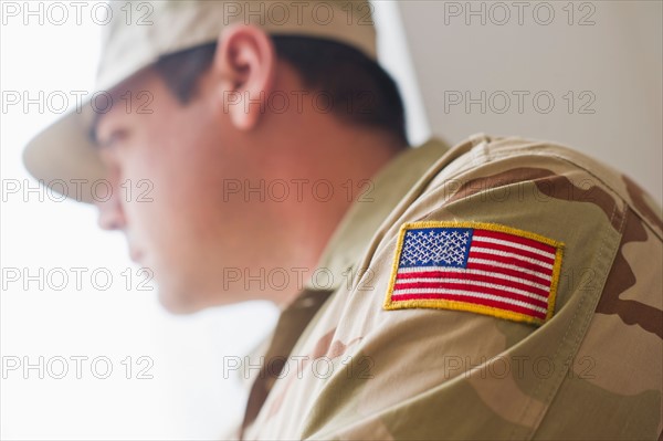 Man wearing military uniform looking through window. Photo : Daniel Grill