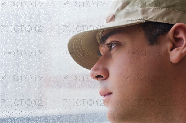 Man wearing military uniform looking through window. Photo : Daniel Grill