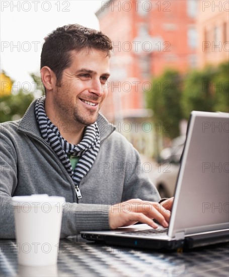 Man with laptop sitting in outdoor cafe. Photo : Daniel Grill