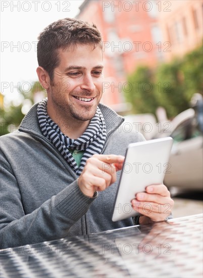 Man with digital tablet sitting in outdoor cafe. Photo : Daniel Grill